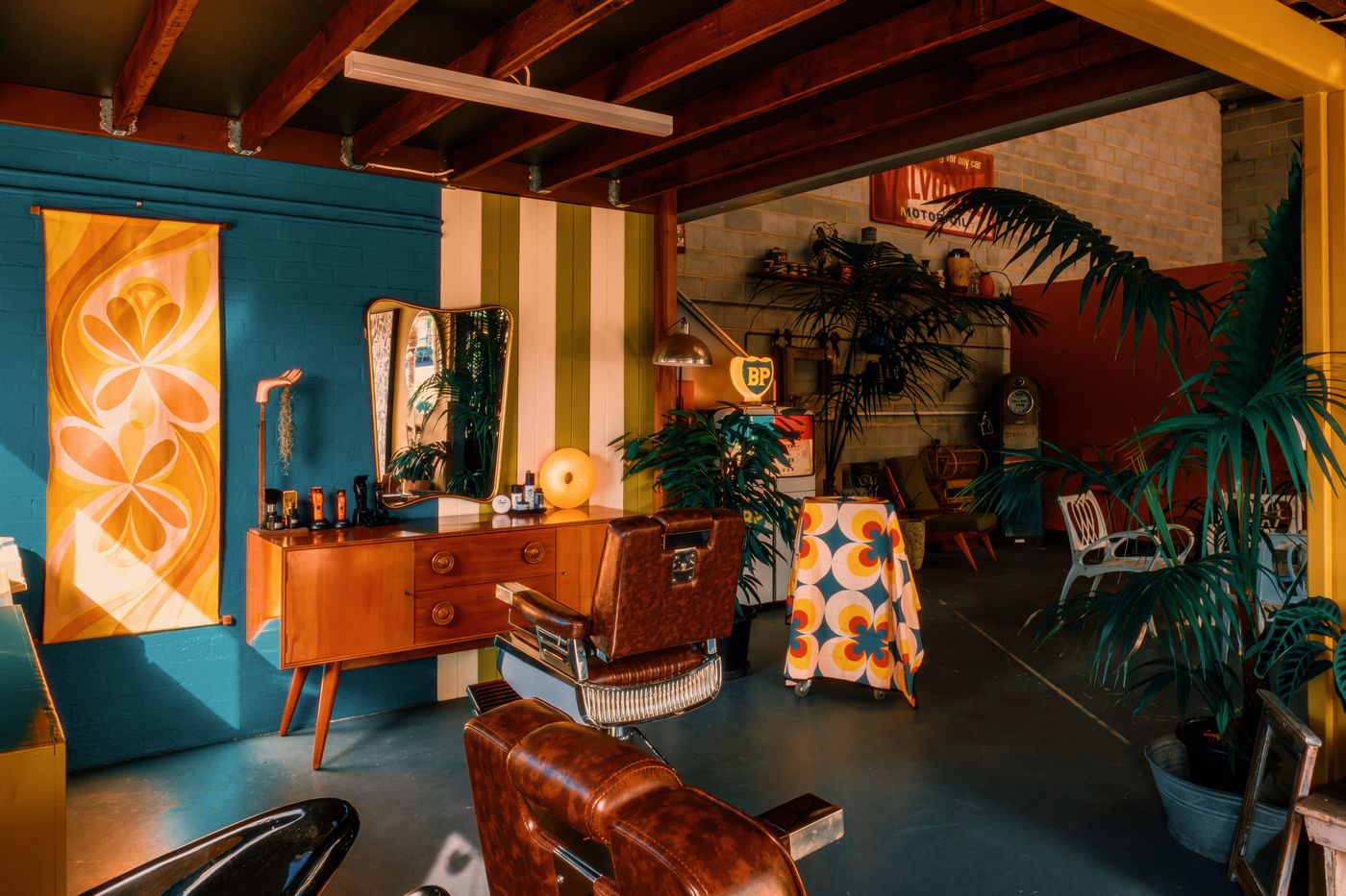 Wide view of the Spunk studio with barber chairs, teal and mustard walls, and vintage decor